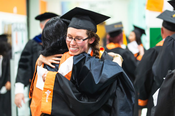 Bachelor's in Marketing students hugging on graduation day